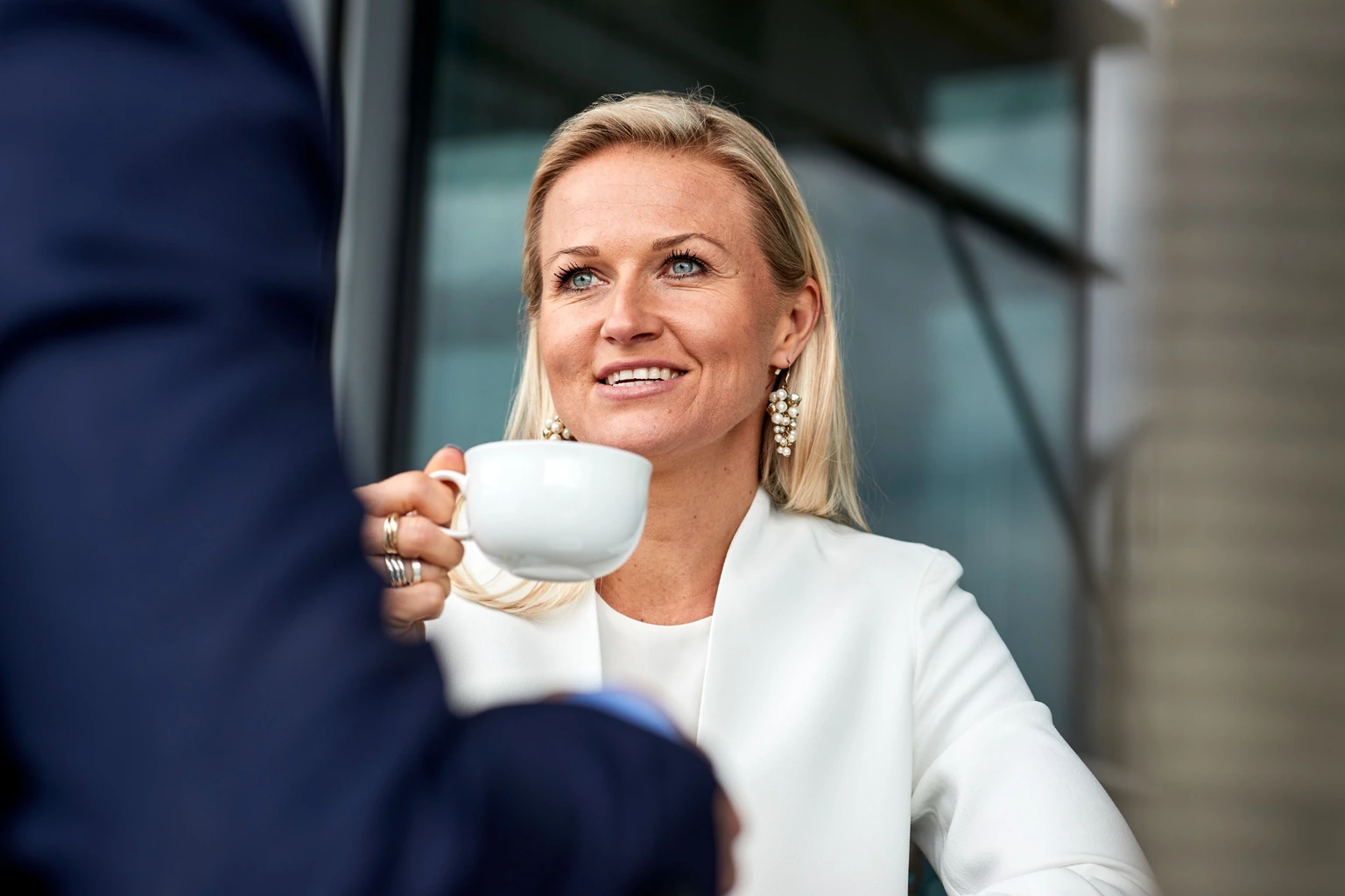 A woman holding a cup during a conversation.