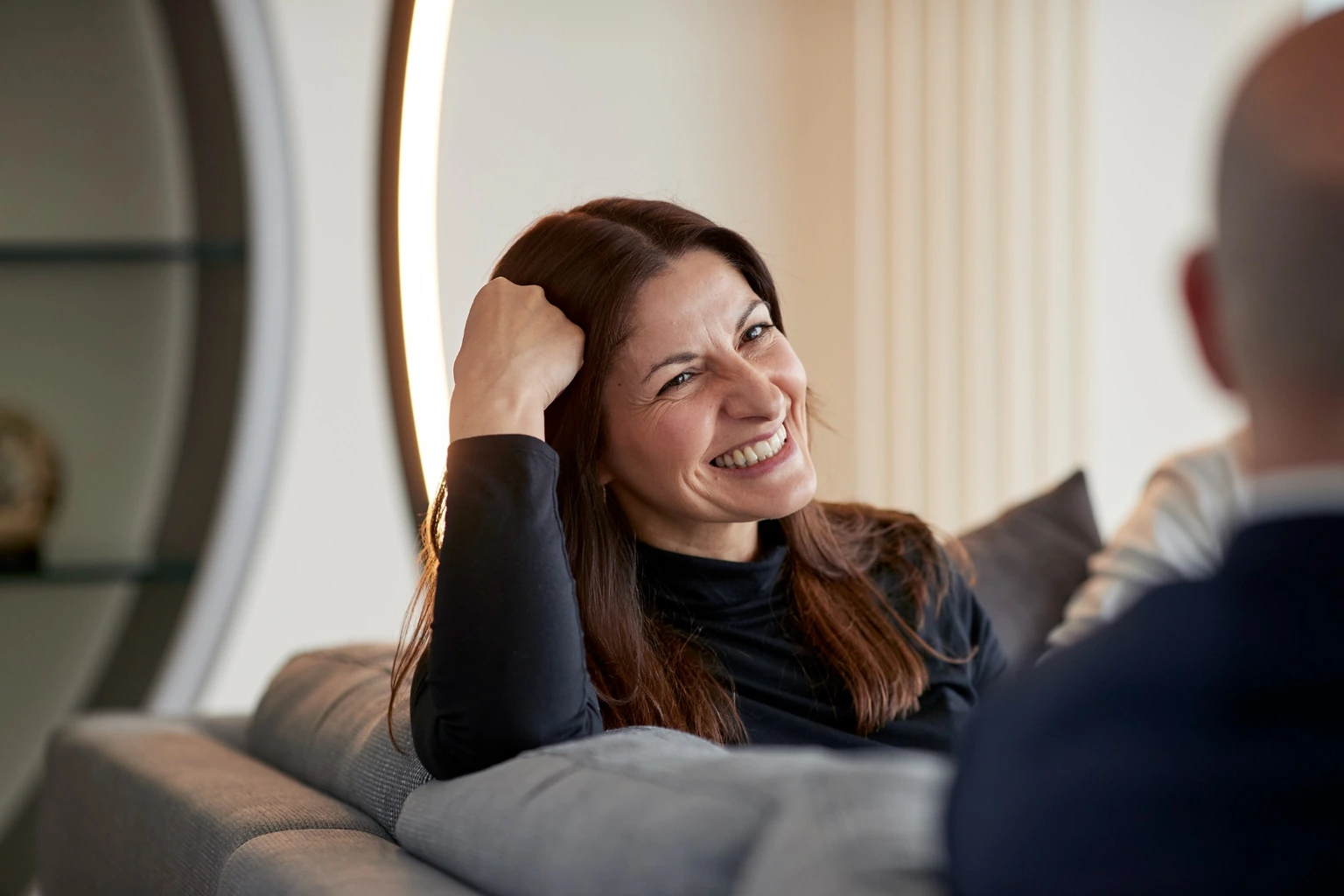 A woman seated on a sofa in conversation.